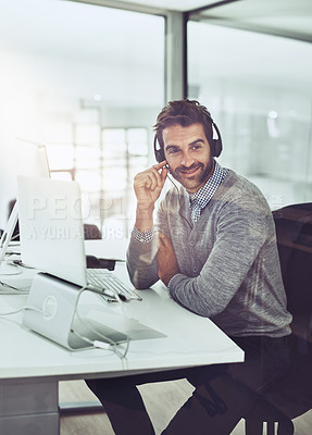 Buy stock photo High angle shot of a handsome young businessman wearing a headset while sitting at his desk