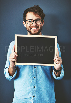 Buy stock photo Studio portrait of a young man holding a blackboard against a grey background