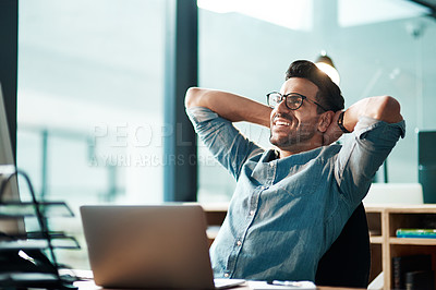 Buy stock photo Shot of a young businessman taking a break at his desk in a modern office