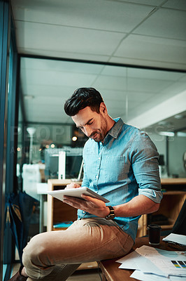 Buy stock photo Shot of a young businessman using a digital tablet in a modern office