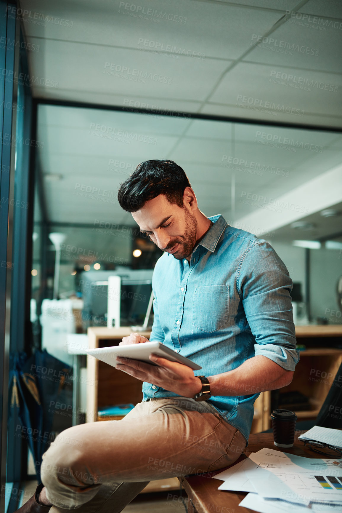 Buy stock photo Shot of a young businessman using a digital tablet in a modern office