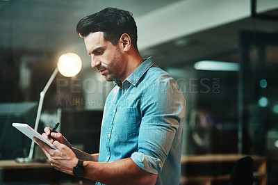 Buy stock photo Serious design business architect thinking and working on his tablet in a modern casual office at night. Professional designer drawing and planning architecture projects on his touch screen display