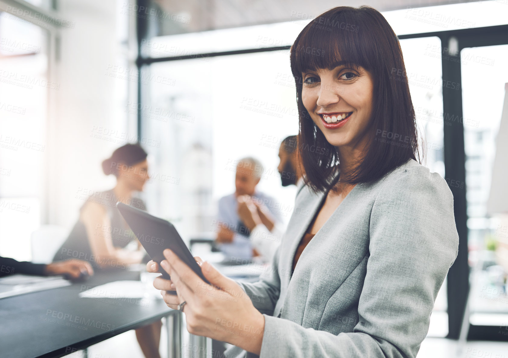 Buy stock photo Cropped portrait of an attractive young businesswoman using her tablet during a meeting in the boardroom