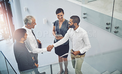 Buy stock photo High angle shot of two businessmen shaking hands while meeting in the office