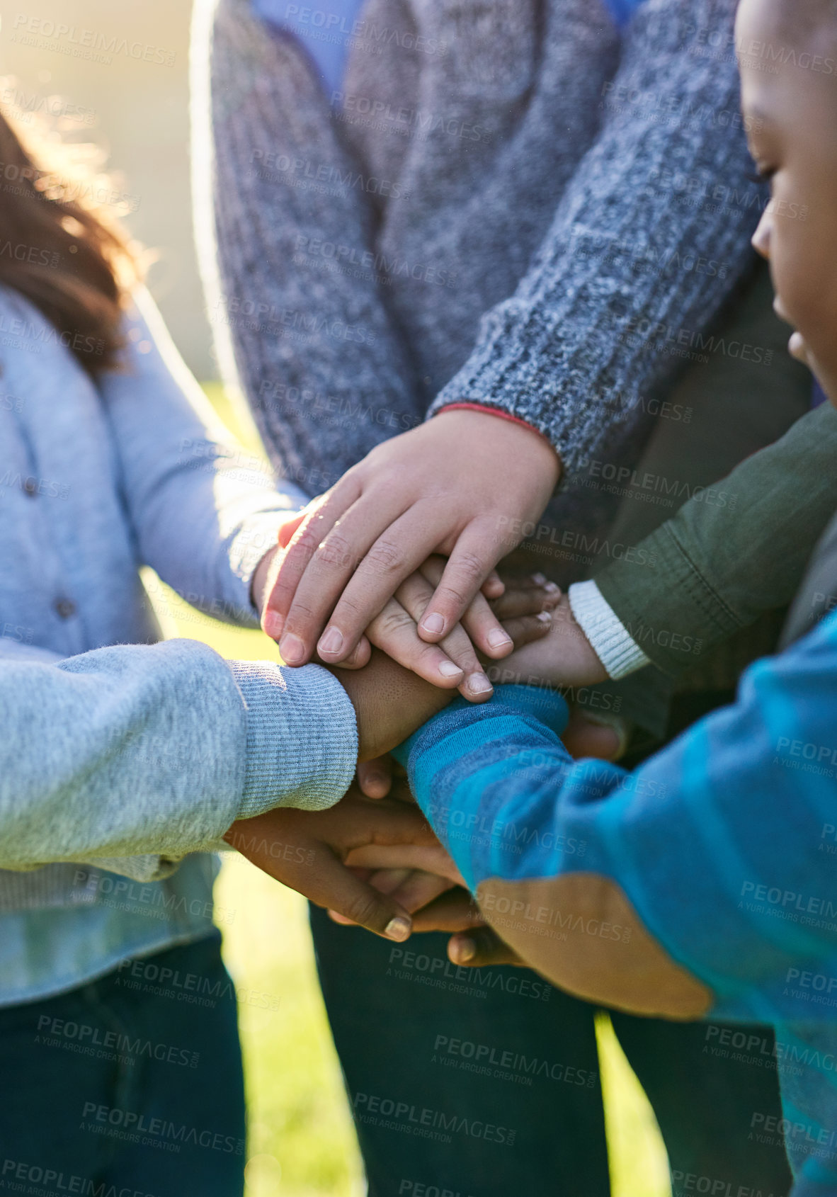 Buy stock photo Shot of a group of unrecognizable elementary school kids joining their hands together in a huddle outside