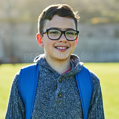 Buy stock photo Boy, child and portrait on field at school with backpack, smile and pride for diversity with education. Kid, glasses and happy on grass with learning, scholarship and future at academy in Canada