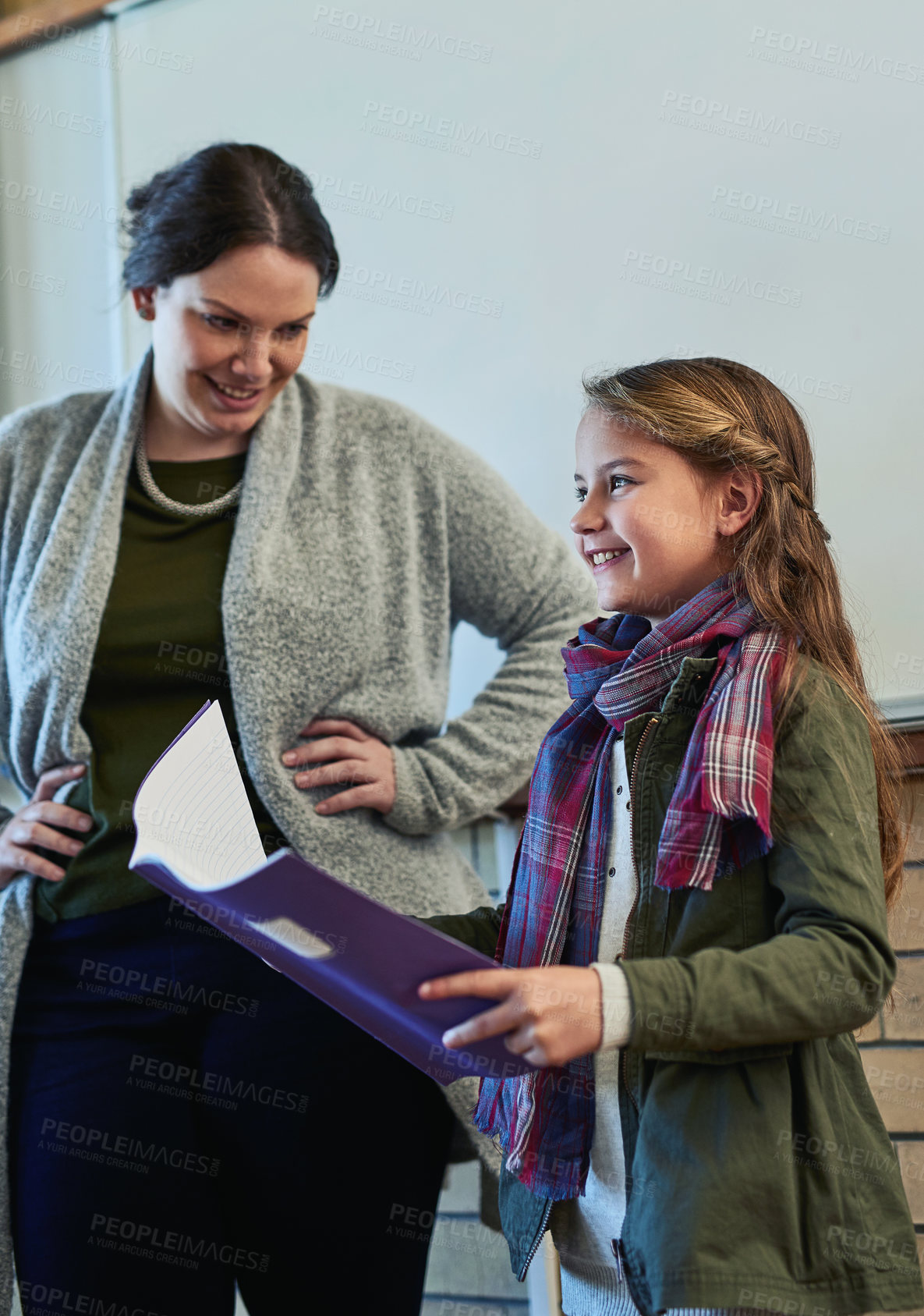 Buy stock photo Shot of an elementary school girl standing alongside her teacher and reading in front of her class