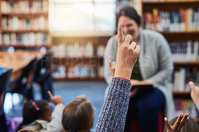 Buy stock photo Shot of an elementary school boy raising his hand to his teacher in the library