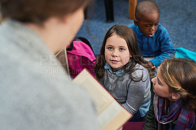 Buy stock photo Shot of a group of elementary school kids listening to their teacher read a story