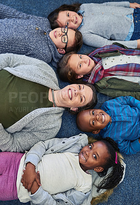 Buy stock photo Portrait of a group of elementary school kids and their teacher lying down on the floor in class