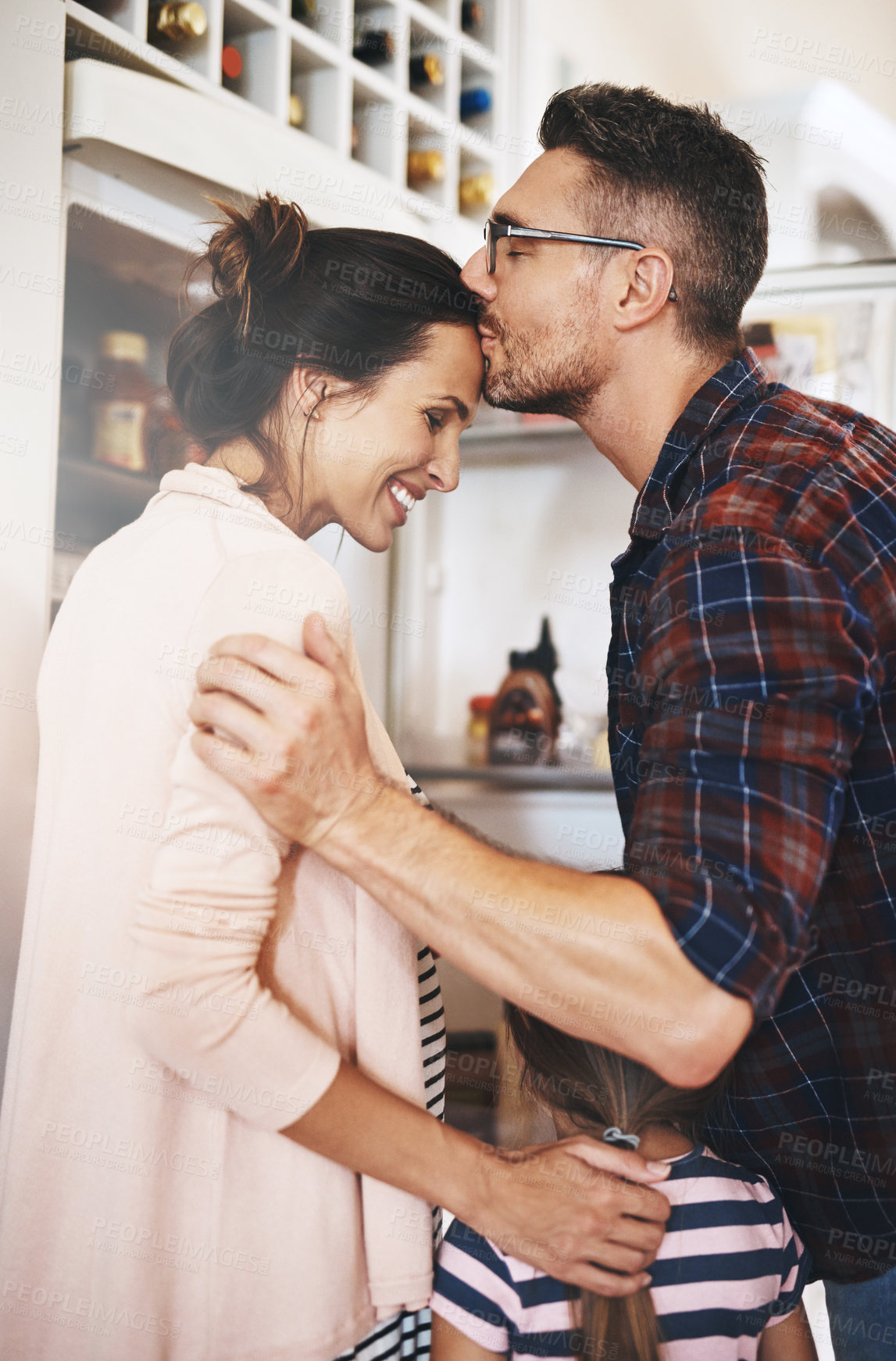 Buy stock photo Shot of a husband lovingly kissing his wife in the kitchen with his family