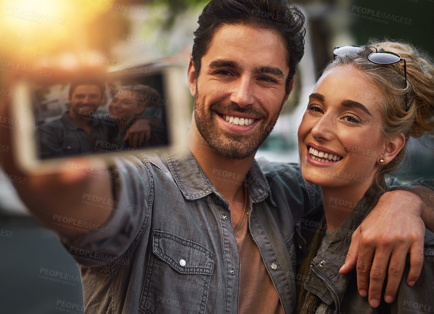 Buy stock photo Couple, selfie and hug with smile in city, care and happy with connection, love and photography. People, man and woman with sunset, profile picture and excited for post on social media in Berlin