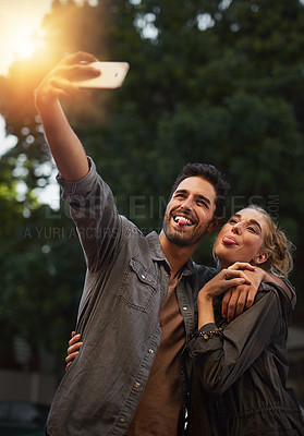 Buy stock photo Shot of a young couple taking a selfie in the city