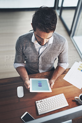 Buy stock photo High angle shot of a young businessman working on a digital tablet in an office