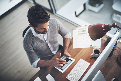 Buy stock photo High angle shot of a young businessman working on a digital tablet in an office
