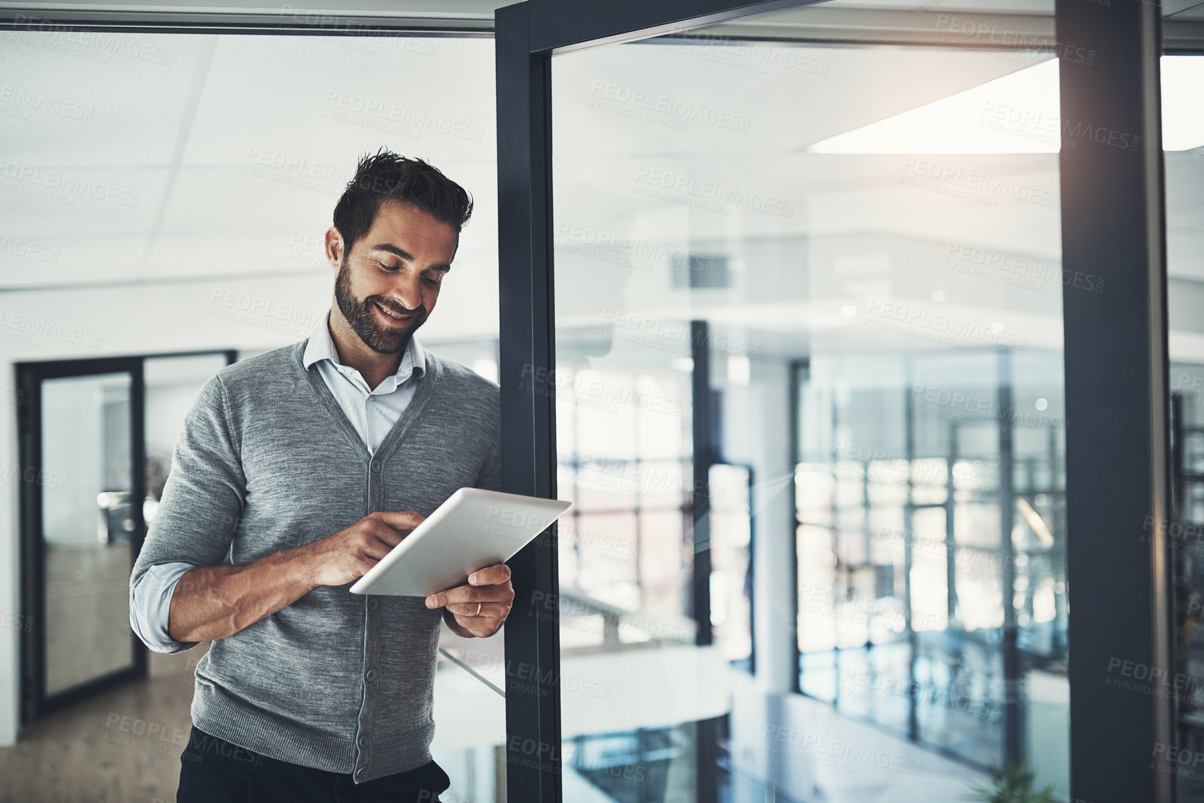 Buy stock photo Shot of a young businessman working on a digital tablet in an office