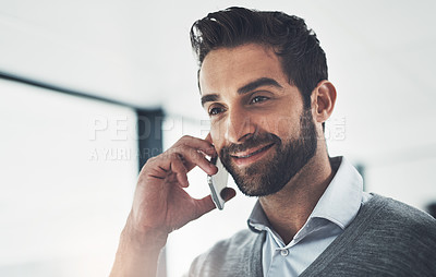 Buy stock photo Shot of a young businessman talking on his cellphone in an office