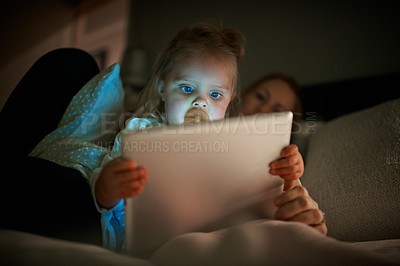 Buy stock photo Shot of an adorable little girl using a digital tablet with her mother at home