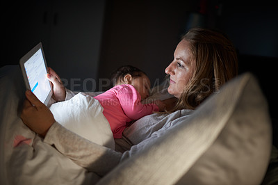 Buy stock photo Shot of a mother using a digital tablet while her baby sleeps on her chest at home