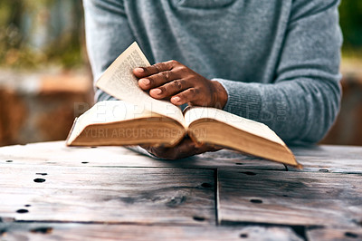 Buy stock photo Hands, religion and a man reading the bible at a table outdoor in the park for faith or belief in god. Book, story and spiritual with a male christian sitting in the garden for learning or worship
