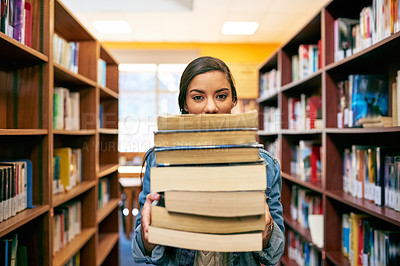 Buy stock photo Portrait of a university student holding a pile of books in the library at campus