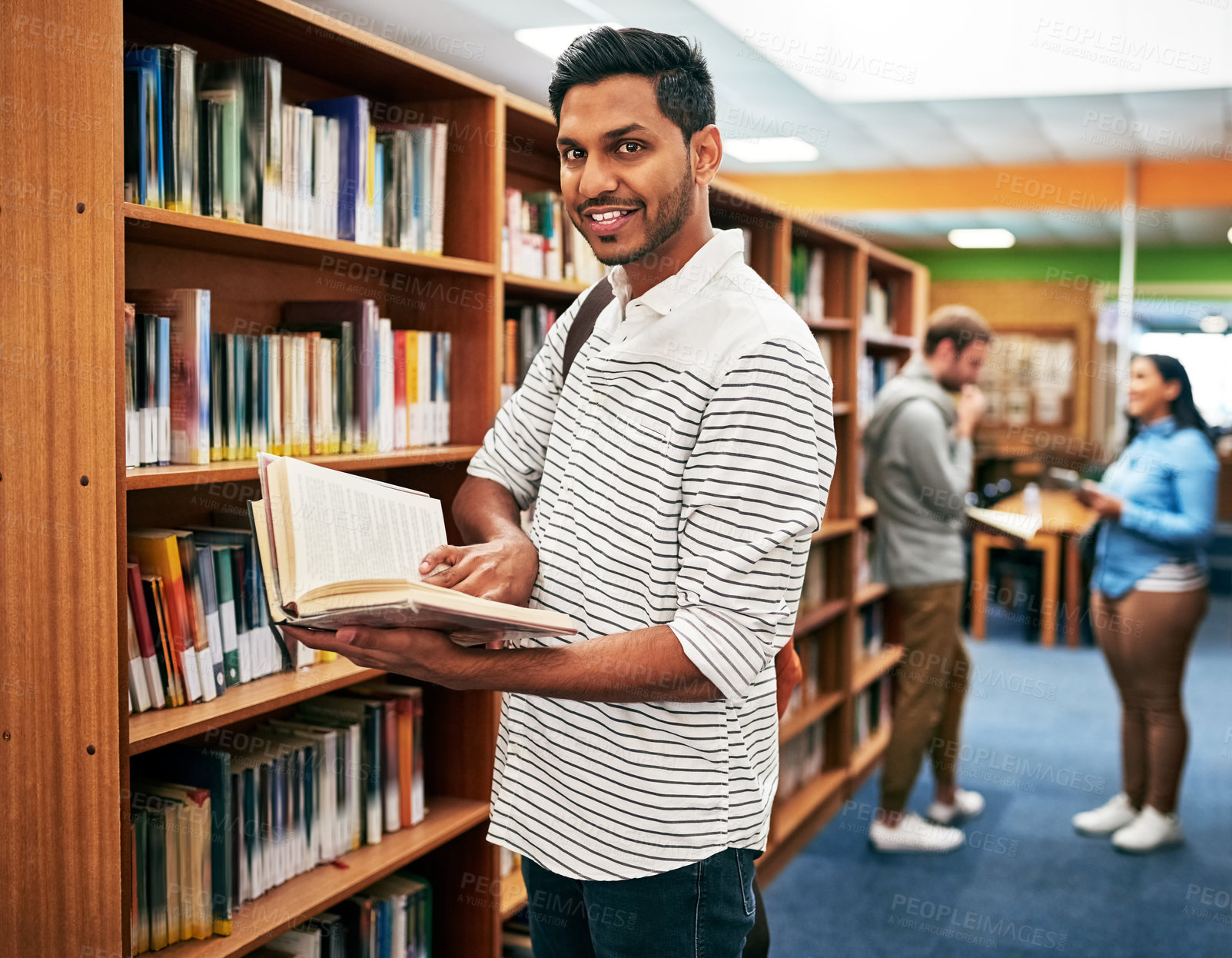 Buy stock photo Portrait of a university student reading a book in the library at campus