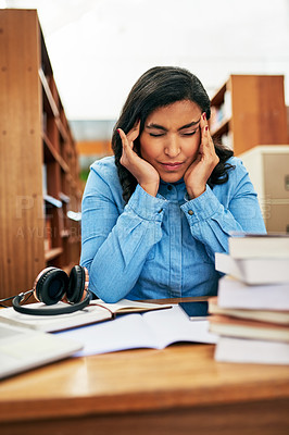 Buy stock photo Shot of a university student looking stressed out while working in the library at campus