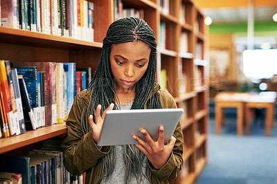 Buy stock photo Shot of a university student using a digital tablet in the library at campus