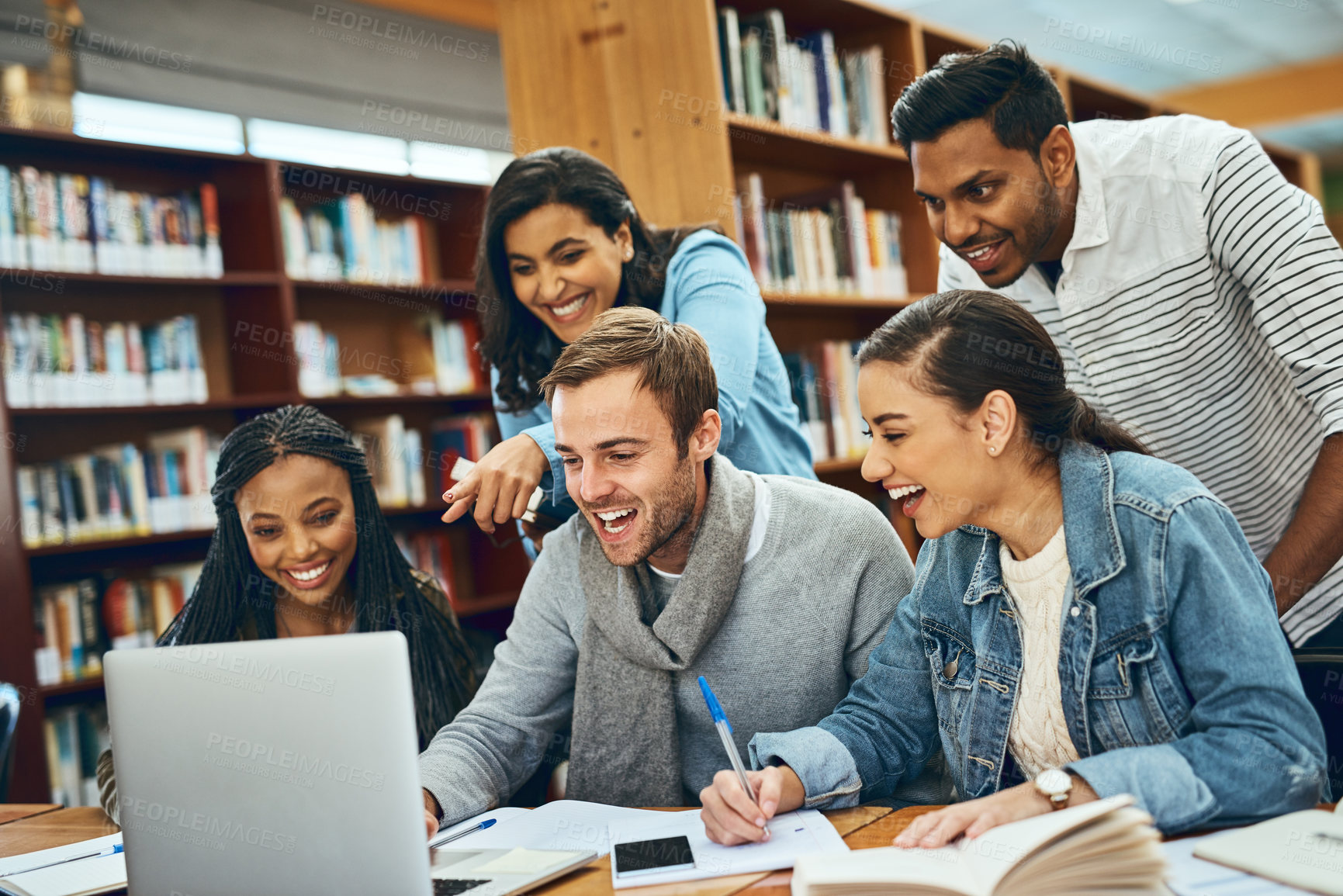 Buy stock photo Education, students and laughing at laptop in library for research project, funny meme and creative assignment. Diversity study group, books and people with learning at college for test preparation