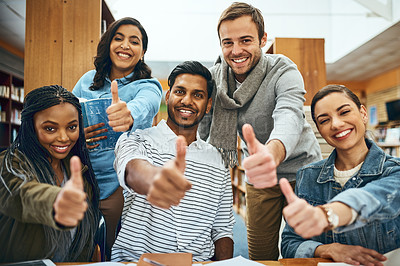 Buy stock photo Cropped portrait of a group of university students showing you thumbs up while studying in the library