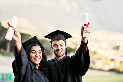Buy stock photo Portrait of two students celebrating with their diplomas on graduation day