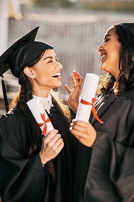 Buy stock photo Shot of two students holding their diplomas on graduation day