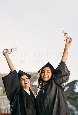Buy stock photo Portrait of two students celebrating with their diplomas on graduation day
