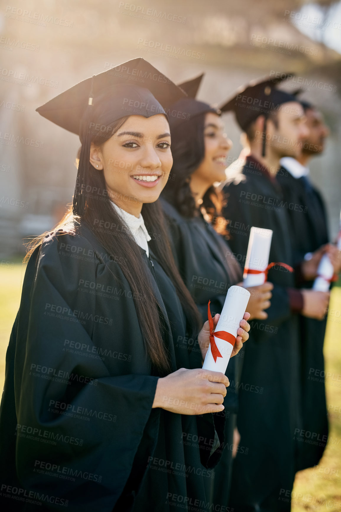 Buy stock photo Shot of a group of students standing in a line on graduation day