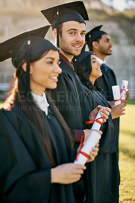 Buy stock photo Shot of a group of students standing in a line on graduation day