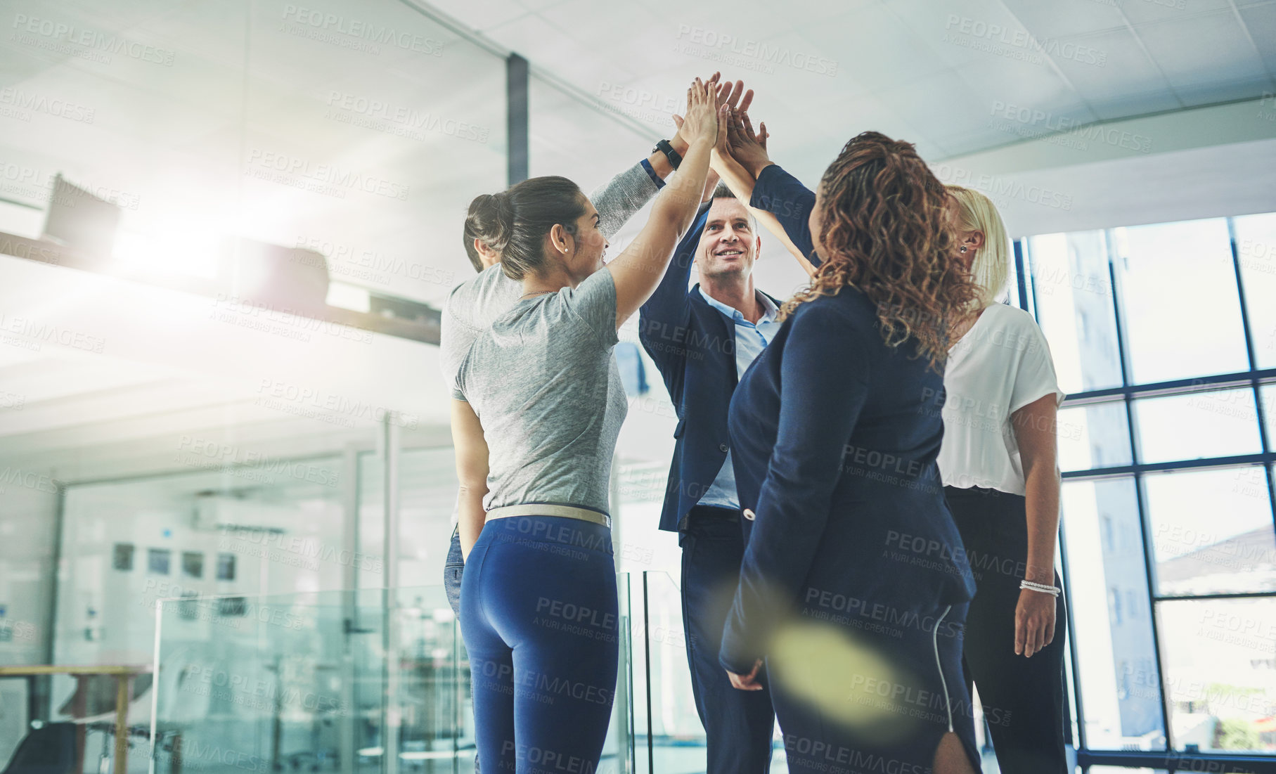 Buy stock photo Shot of a diverse group of coworkers high fiving together in an office