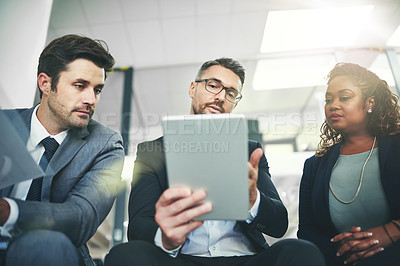 Buy stock photo Shot of a group of coworkers talking together over a digital tablet in an office