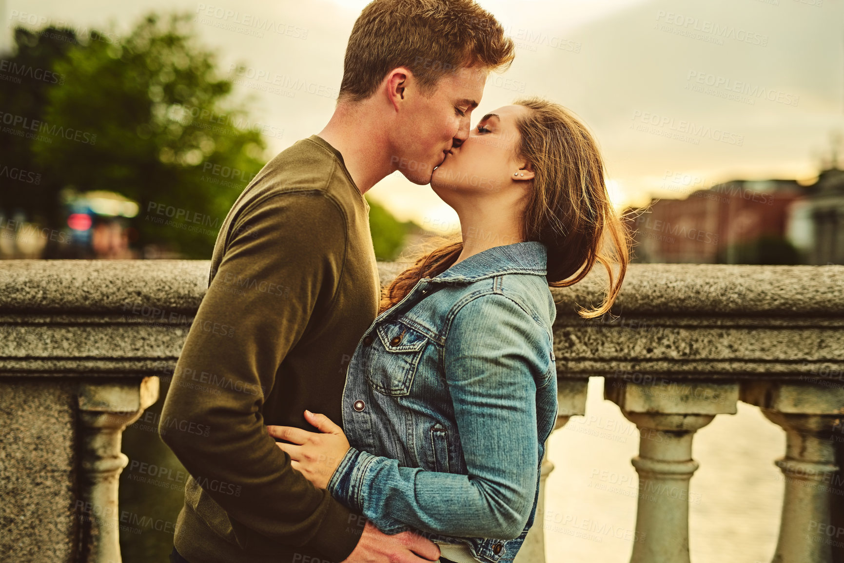 Buy stock photo Cropped shot of a loving young couple sharing a kiss while out on a date