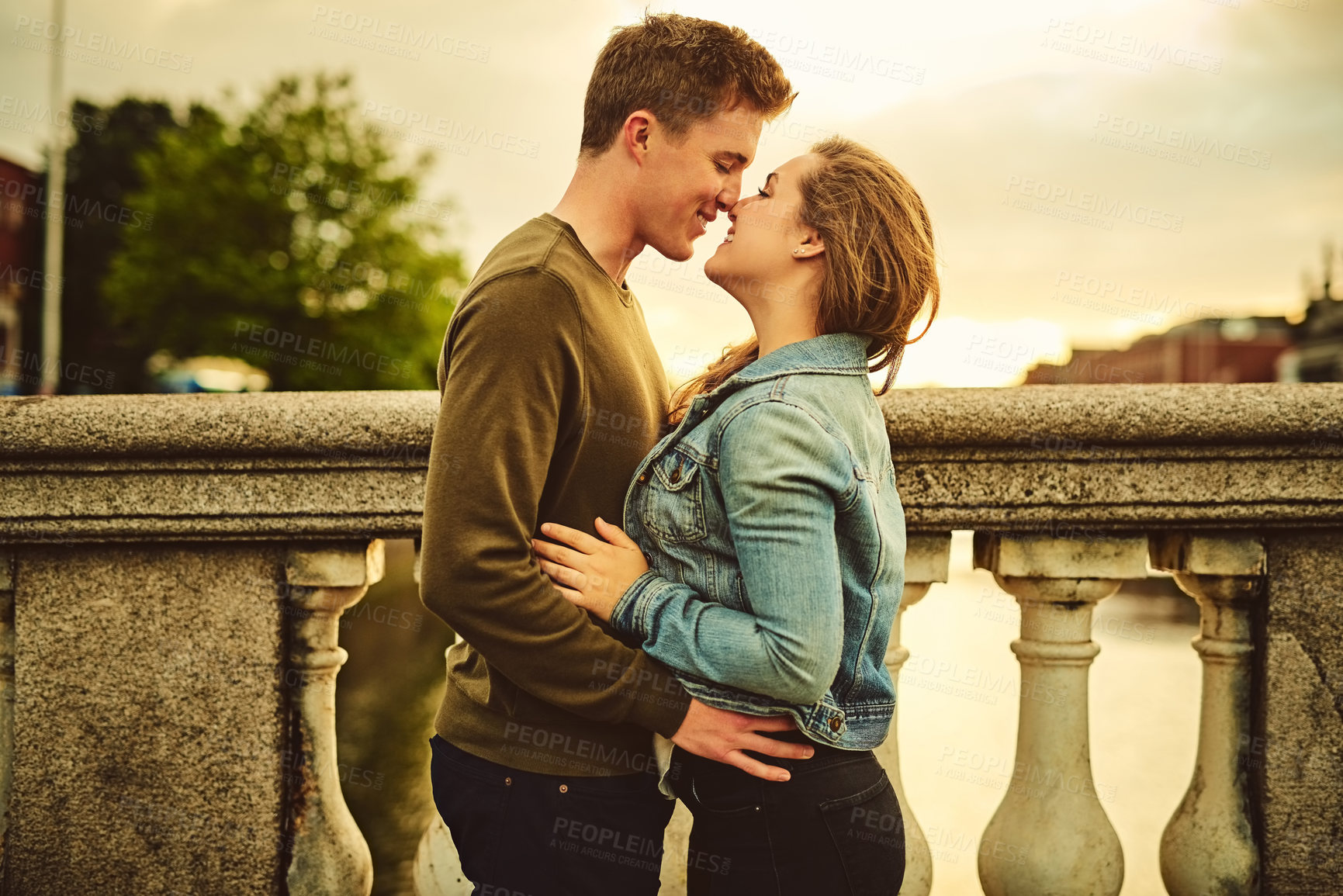 Buy stock photo Happy couple, kiss and hug with love in city for embrace, affection or intimacy on outdoor holiday together. Young man, woman or lovers touching for romantic date, commitment or care in an urban town