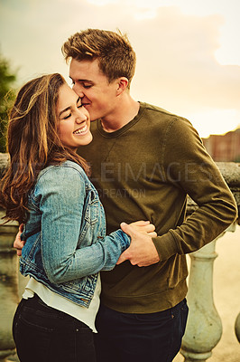 Buy stock photo Couple, outdoor and kiss on cheek, love and bonding on date, smile and outing for anniversary in morning. Embrace, woman and man in vacation for celebration of marriage, honeymoon and commitment