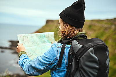 Buy stock photo Shot of a young man looking at a map for directions outdoors