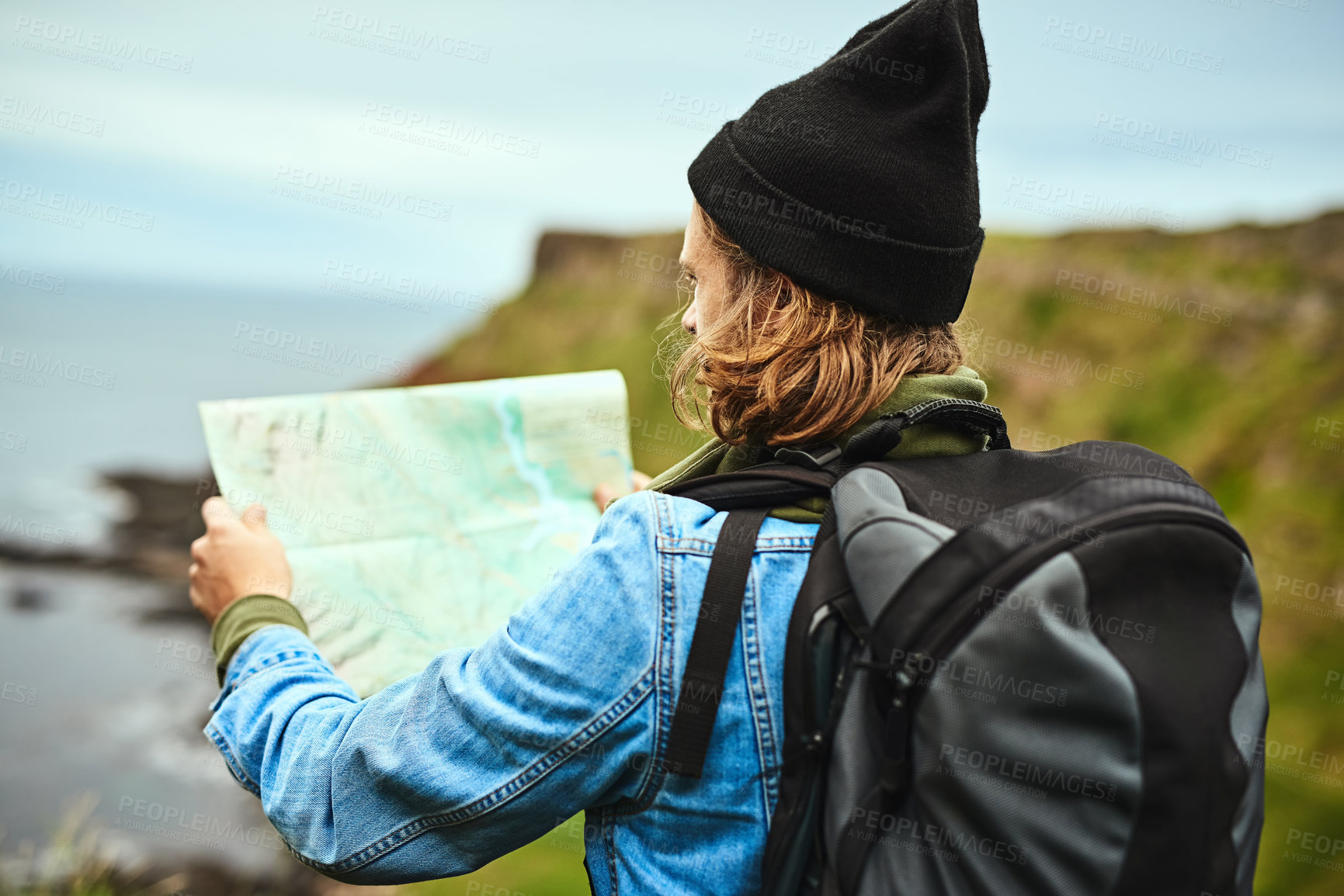 Buy stock photo Shot of a young man looking at a map for directions outdoors