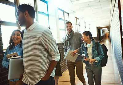 Buy stock photo Cropped shot of a group of university students walking through a campus corridor