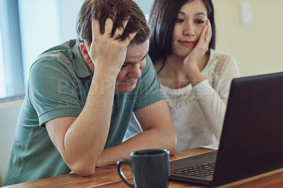 Buy stock photo Shot of a stressed couple sitting in front on their laptop  at home