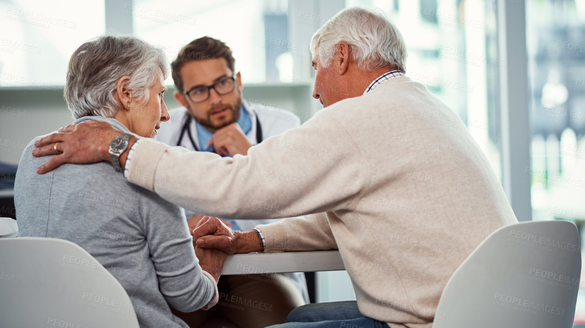 Buy stock photo Shot of a senior man consoling his wife during a consultation with a doctor in a clinic