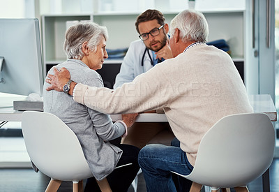 Buy stock photo Shot of a senior man consoling his wife during a consultation with a doctor in a clinic