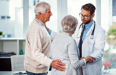 Buy stock photo Shot of a doctor comforting a senior couple in a clinic