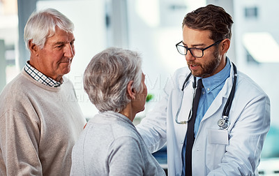 Buy stock photo Shot of a doctor consulting with a senior couple in a clinic