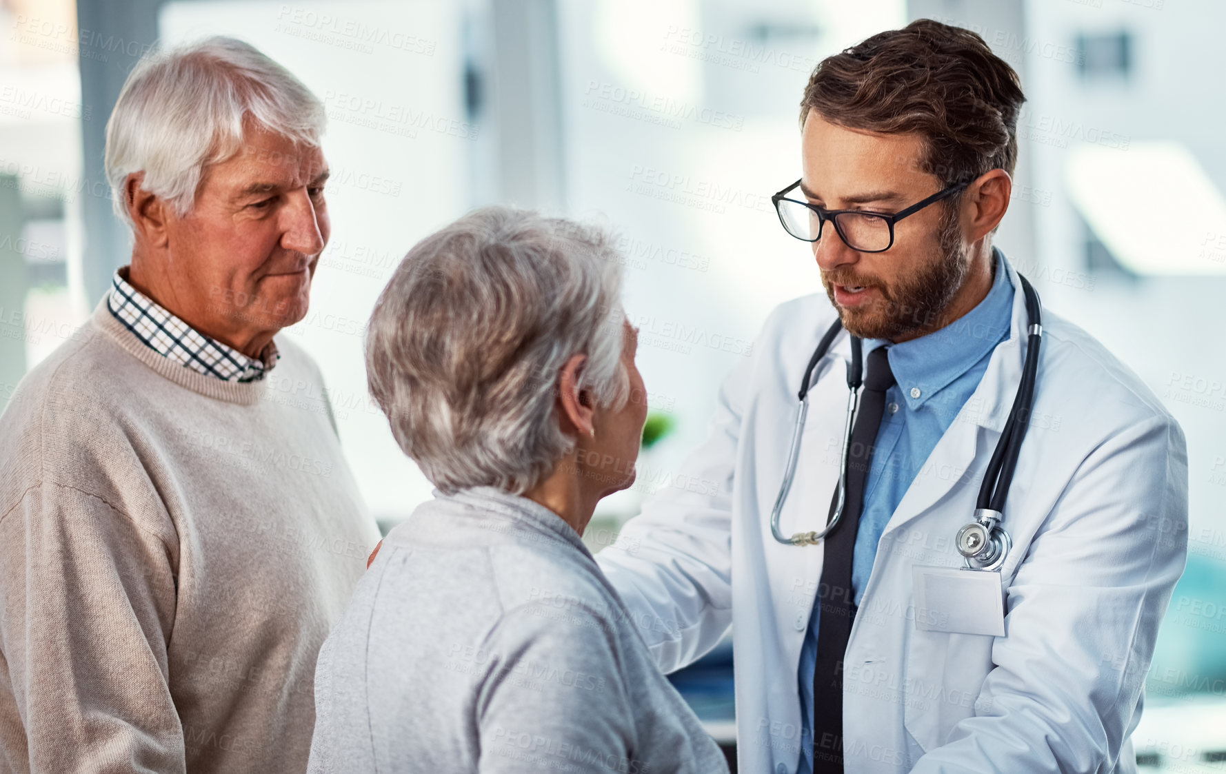 Buy stock photo Shot of a doctor consulting with a senior couple in a clinic