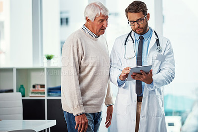 Buy stock photo Shot of a doctor discussing something on a digital tablet with a senior patient in a clinic